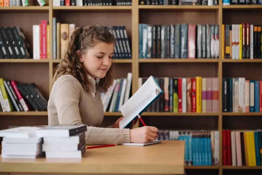 Book Recommendations for Your Next Literary Escape girl studying among books sitting at the desk among books