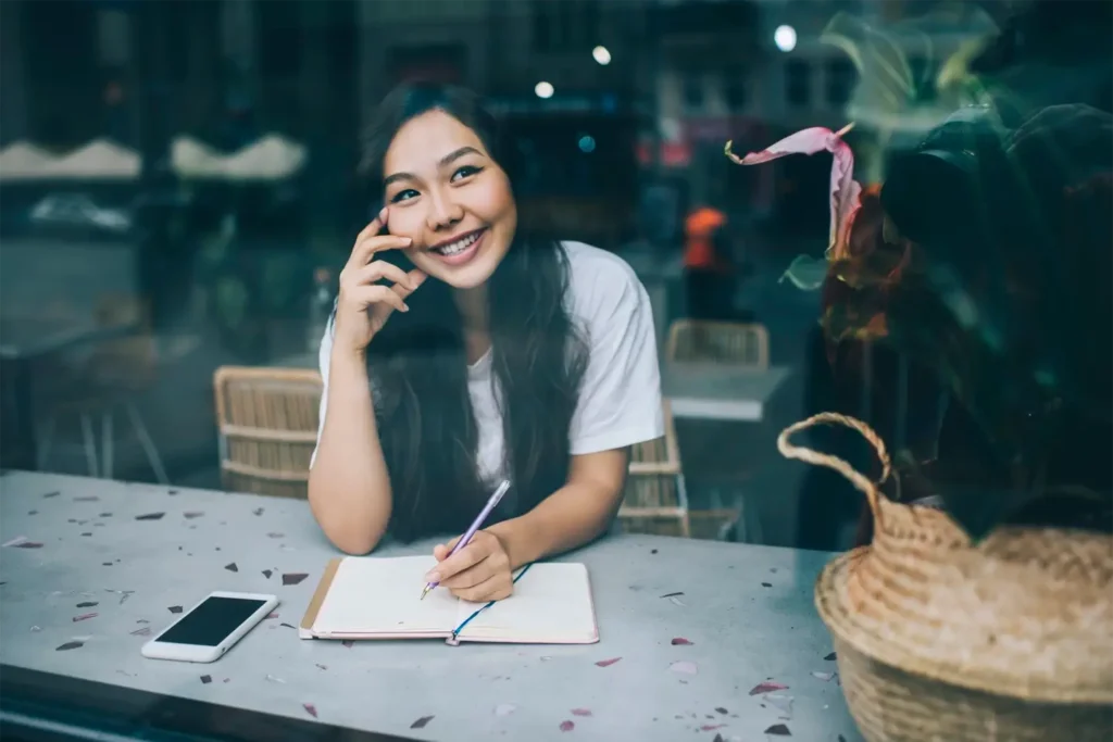Unlock Your Writing Potential Tips and Techniques for Authors happy ethnic female writer in cafe with notebook and smartphone